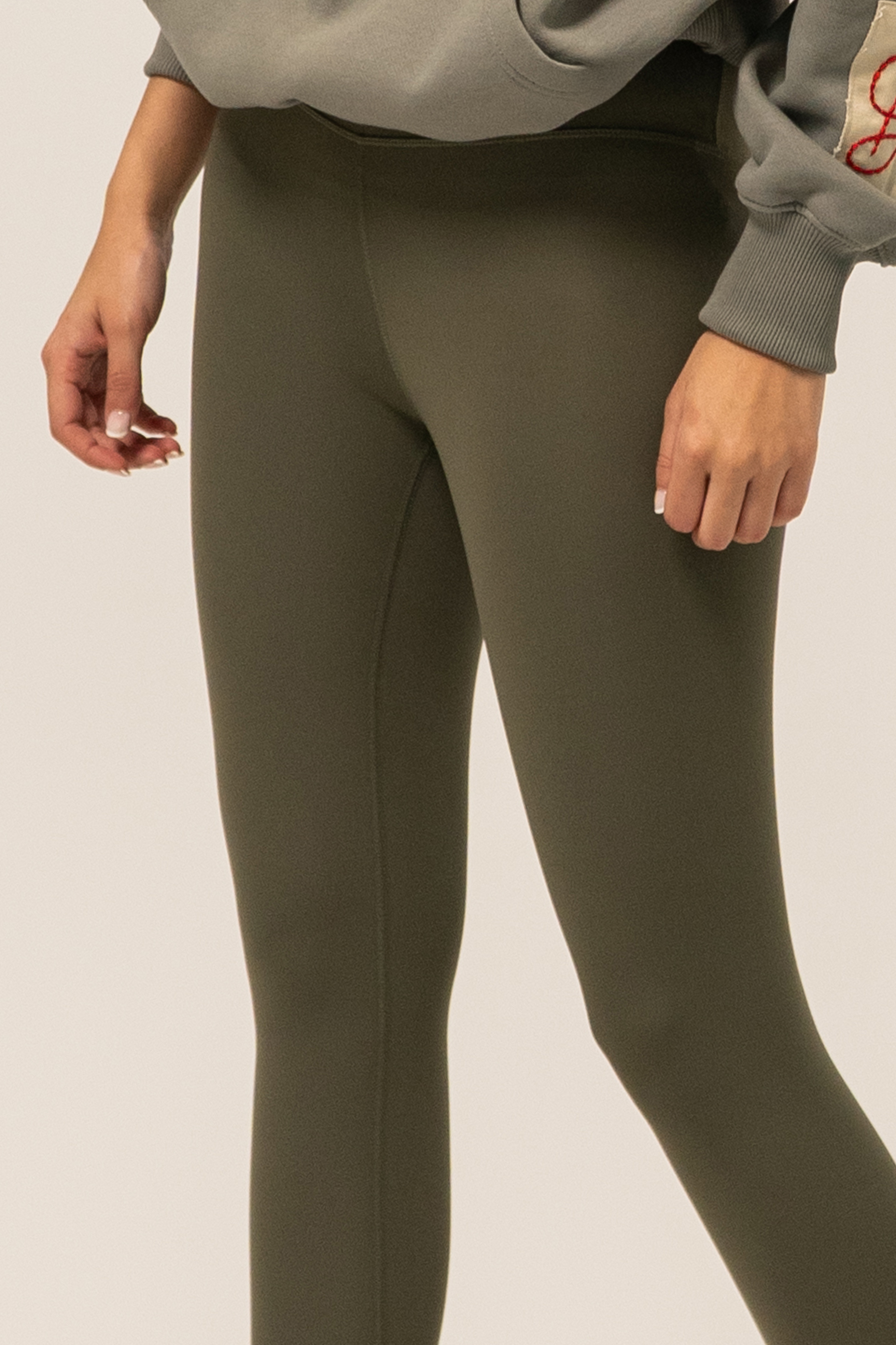 Olive green leggings worn by a person on a plain background